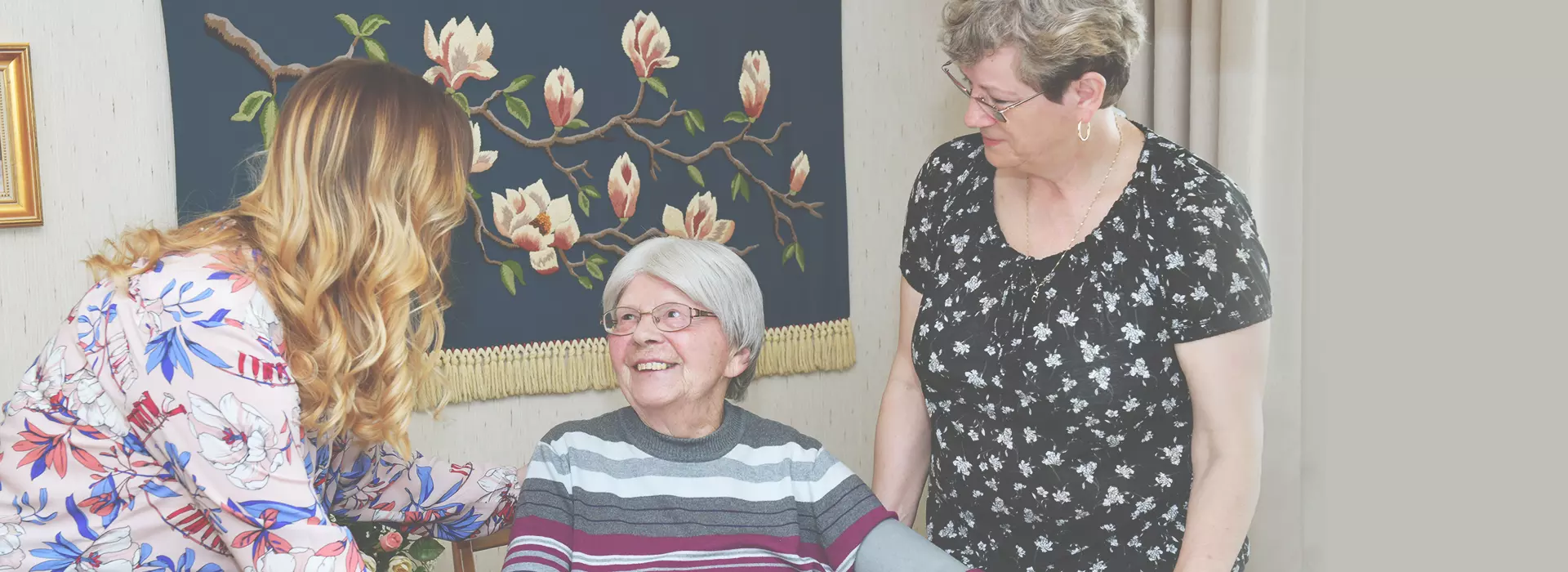 Betreuungskräfte im Gespräch mit einer älteren Frau zu Hause