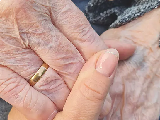Hand einer Betreuungskraft hält behutsam die Hand einer älteren Person